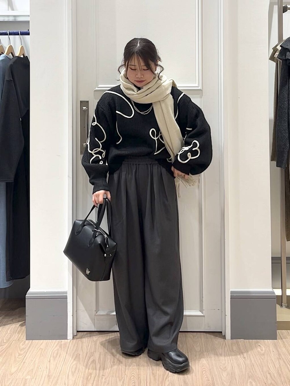 ブラック系のショルダーバッグ、ブラック系のニット/セーター、グレー系のその他パンツを着用したレディースの冬コーディネートの2枚目の写真