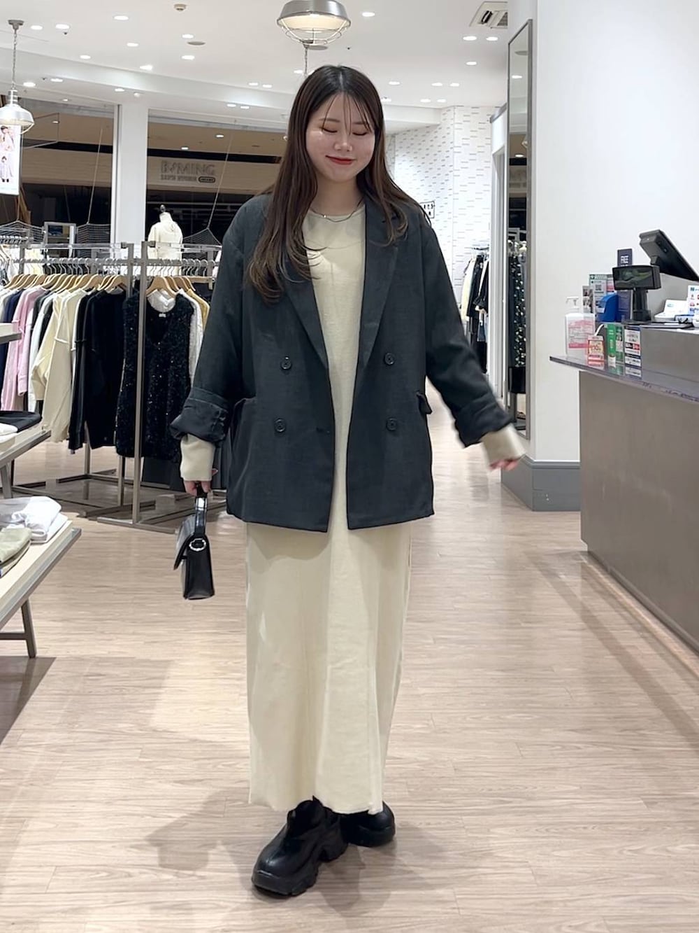 ブラック系のブーツ、ブラック系のショルダーバッグ、グレー系のテーラードジャケットを着用したレディースの冬コーディネートの4枚目の写真