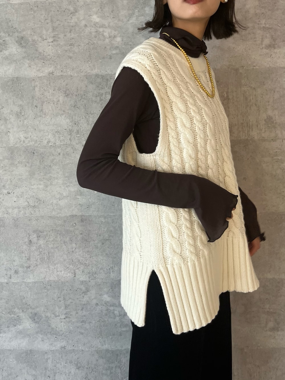 ホワイト系のベスト、ブラック系のその他パンツ、ブラック系のブーツを着用したレディースの秋コーディネートの2枚目の写真