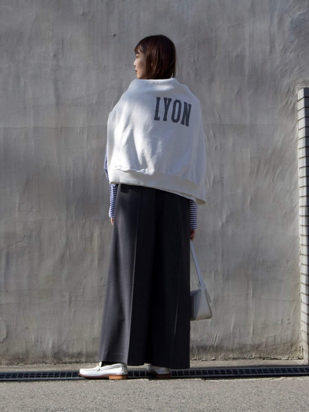 ブルー系のシャツ/ブラウス、ホワイト系のスウェット、グレー系のジャンパースカートを着用したレディースの冬コーディネートの2枚目の写真