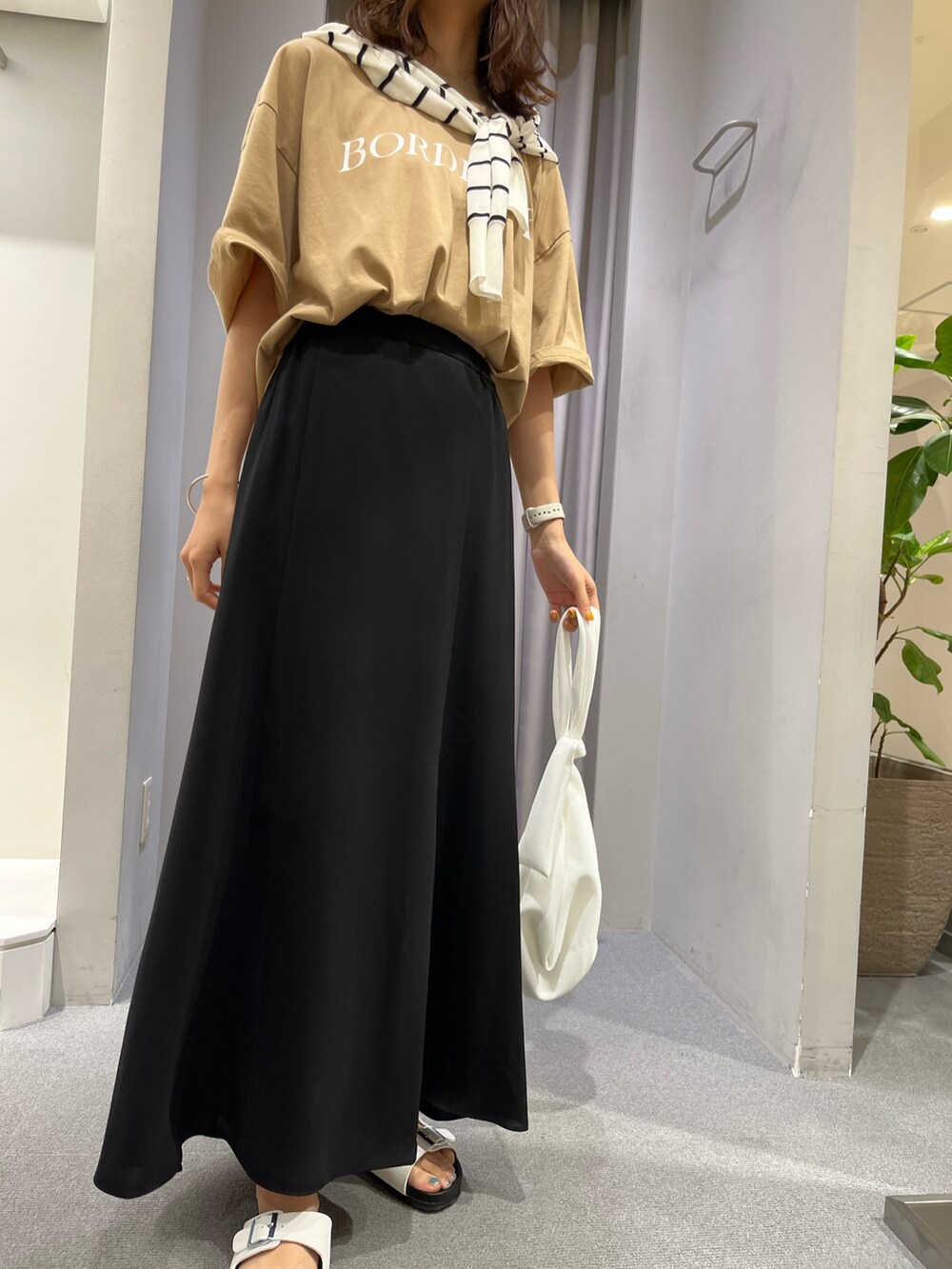 ベージュ系のTシャツ/カットソー、ブラック系のスカート、ホワイト系のサンダルを着用したレディースの夏コーディネートの2枚目の写真