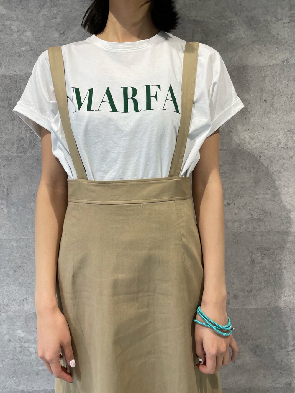 ベージュ系のスカート、ホワイト系のTシャツ/カットソー、ブラック系のショルダーバッグを着用したレディースの春コーディネートの2枚目の写真