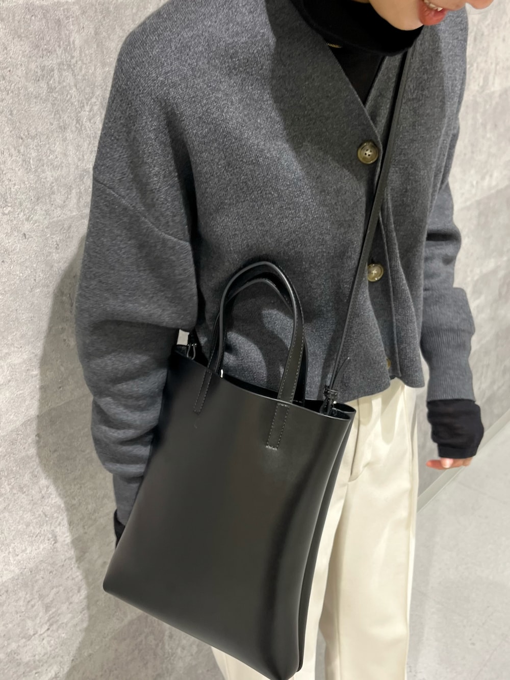 グレー系のカーディガン/ボレロ、ホワイト系のその他パンツ、ブラック系のトートバッグを着用したレディースの秋コーディネートの2枚目の写真