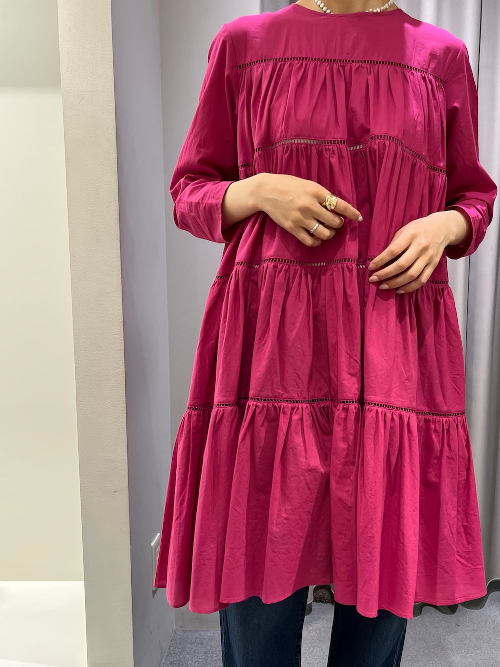 ピンク系のワンピース、ブルー系のデニムパンツ、ブラック系のサンダルを着用したレディースの春コーディネートの2枚目の写真