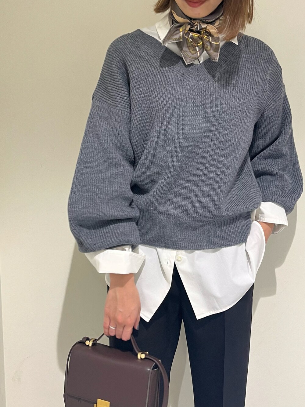 グレー系のニット/セーター、ブラック系のその他パンツ、ホワイト系のシャツ/ブラウスを着用したレディースの秋コーディネートの2枚目の写真