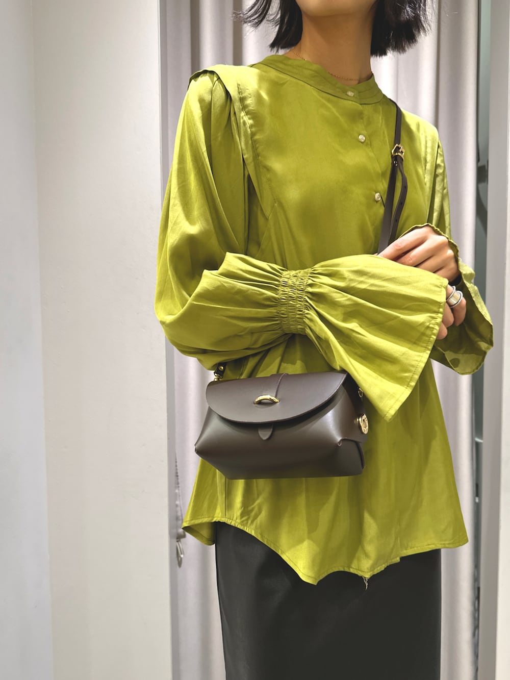 グリーン系のシャツ/ブラウス、グレー系のニット/セーター、ブラック系のスカートを着用したレディースの秋コーディネートの2枚目の写真