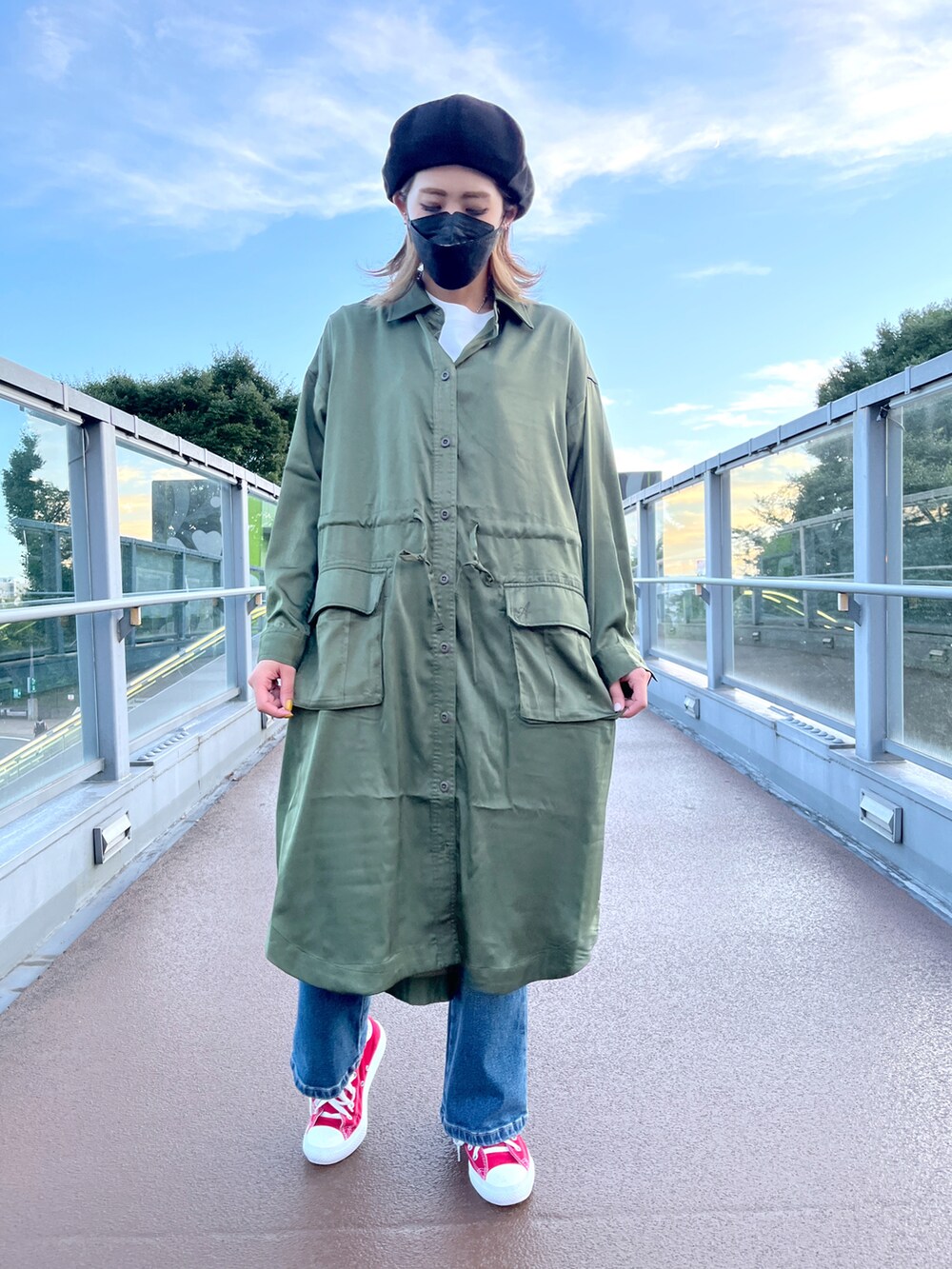 グリーン系のシャツワンピース、ブルー系のデニムパンツ、ホワイト系のTシャツ/カットソーを着用したレディースの秋コーディネートの2枚目の写真