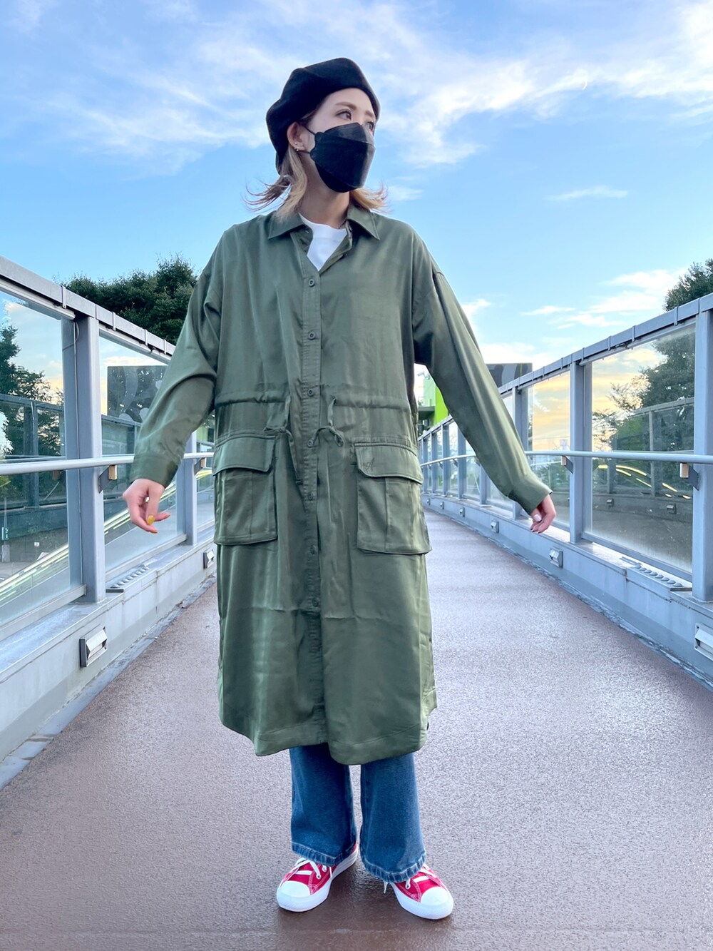 グリーン系のシャツワンピース、ブルー系のデニムパンツ、ホワイト系のTシャツ/カットソーを着用したレディースの秋コーディネートの3枚目の写真