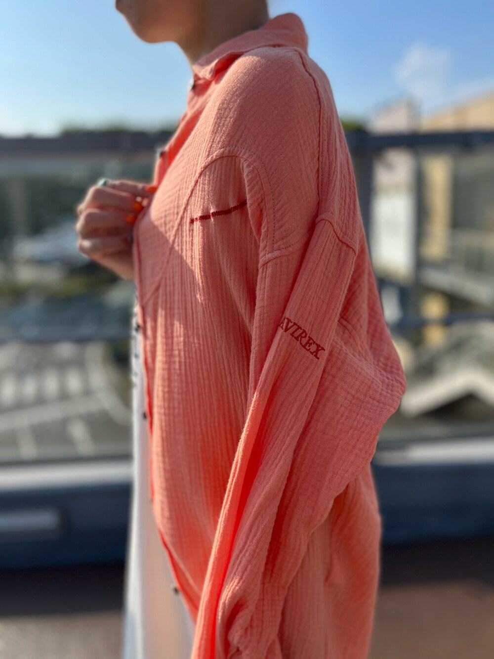 オレンジ系のシャツ/ブラウス、ホワイト系のワンピース、シルバー系のサンダルを着用したレディースの夏コーディネートの2枚目の写真