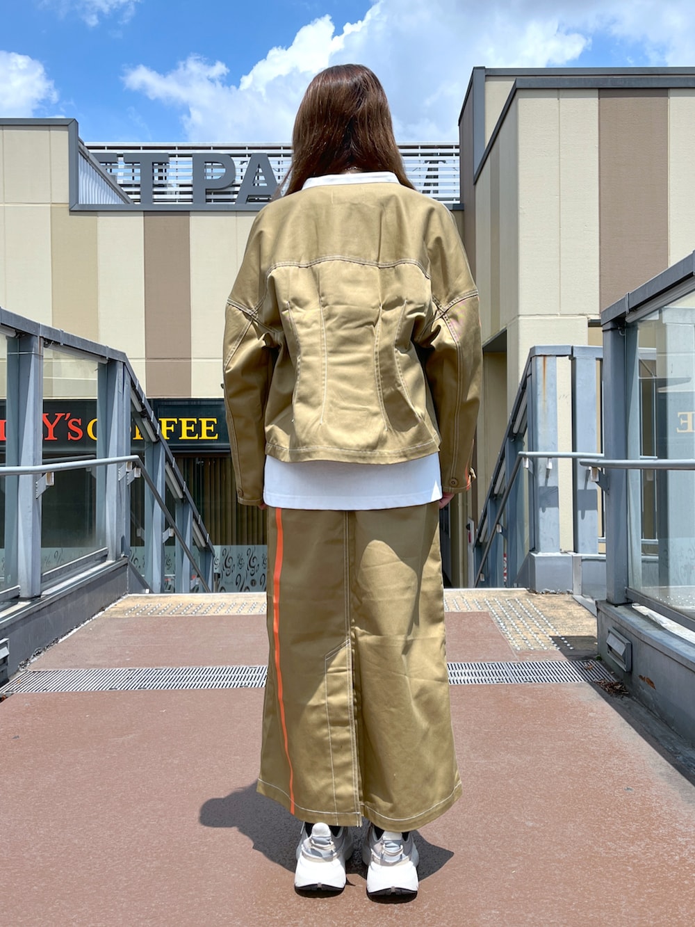 ブラウン系のスカート、ブラウン系のブルゾン、ホワイト系のTシャツ/カットソーを着用したレディースの夏コーディネートの3枚目の写真