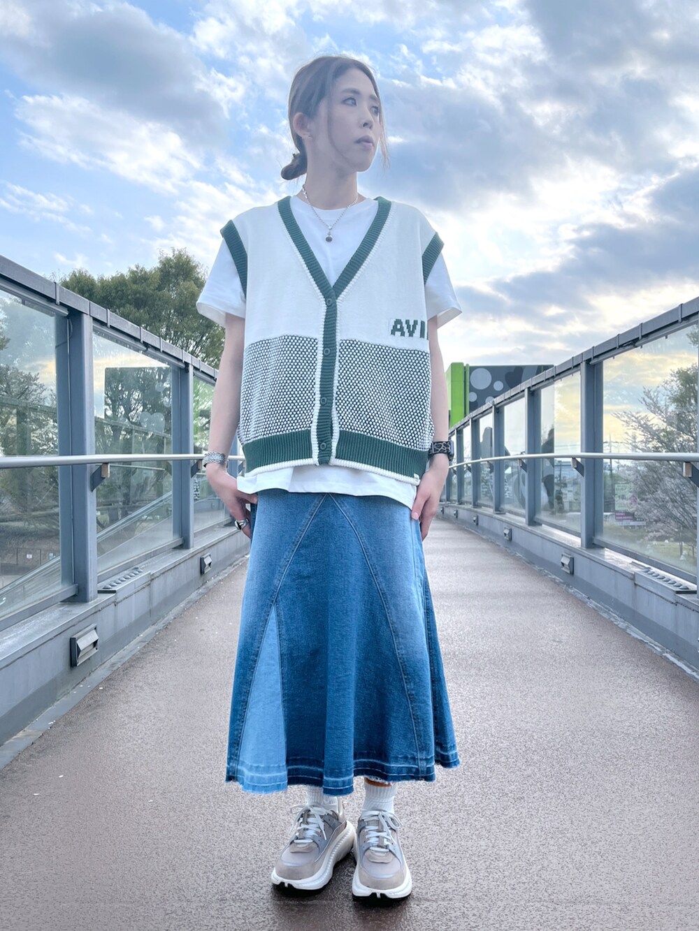 ホワイト系のTシャツ/カットソー、グリーン系のベスト、その他のデニムスカートを着用したレディースの春コーディネートの2枚目の写真