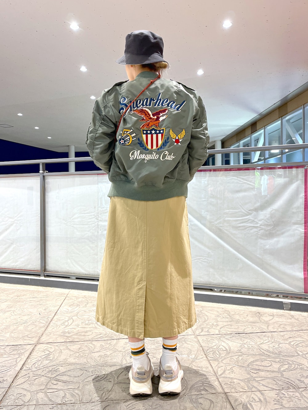 ブラック系のショルダーバッグ、ベージュ系のオールインワン・サロペット、グリーン系のTシャツ/カットソーを着用したレディースの春コーディネートの2枚目の写真