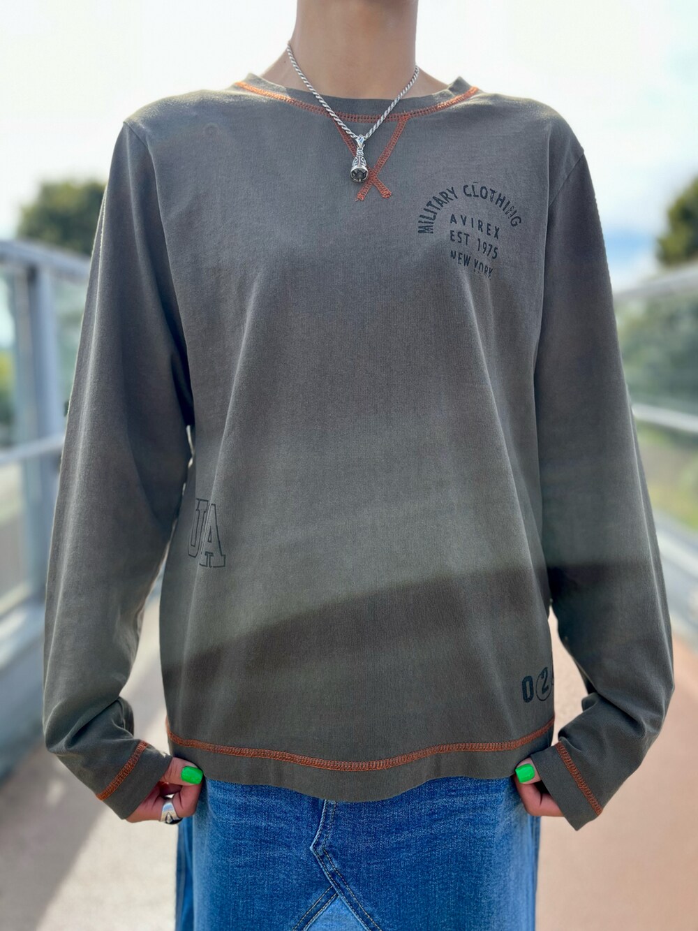 グリーン系のTシャツ/カットソー、グレー系のカーディガン/ボレロ、ブルー系のデニムスカートを着用したレディースの秋コーディネートの2枚目の写真