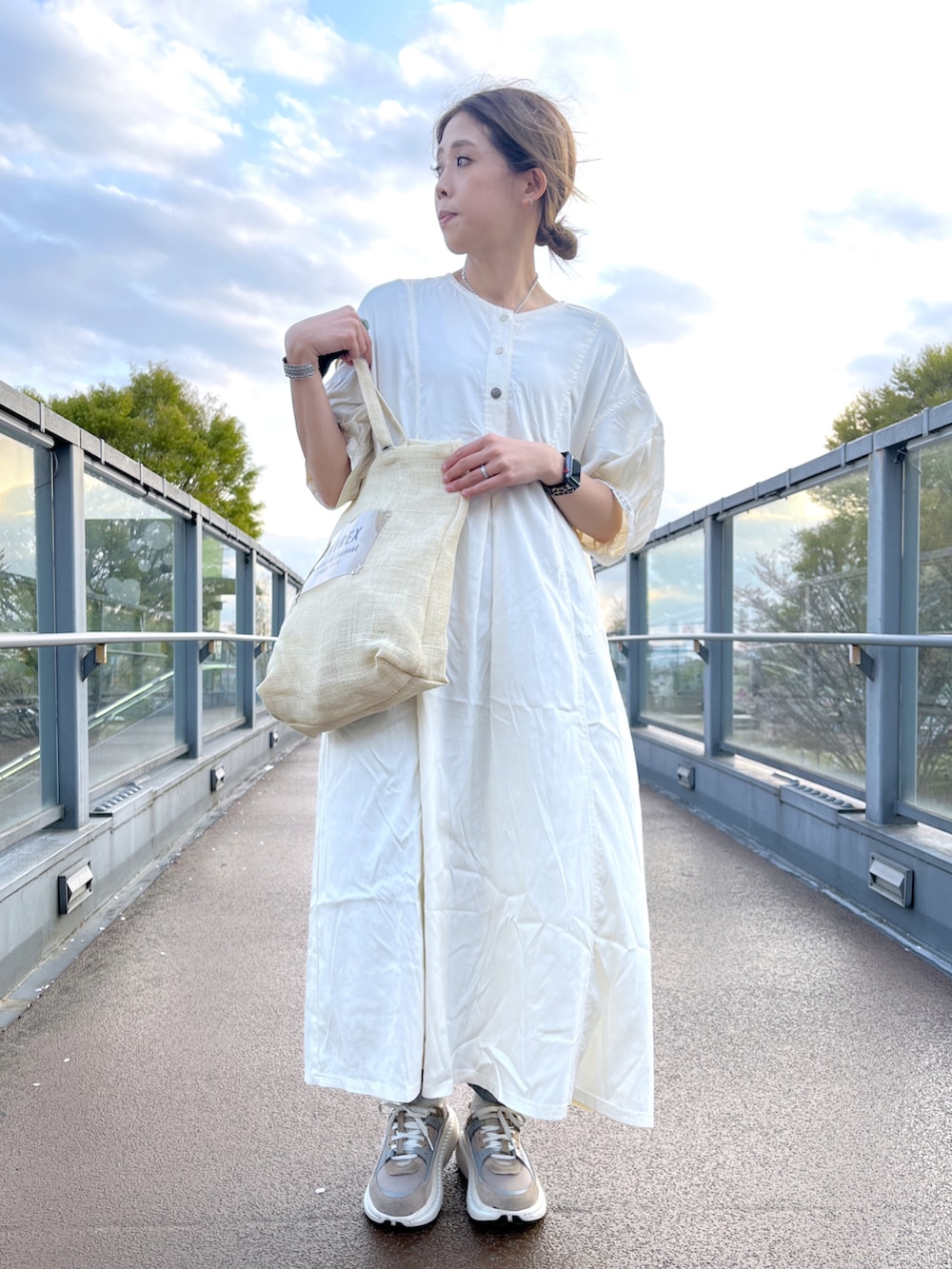 ホワイト系のワンピース、ベージュ系のトートバッグを着用したレディースの春コーディネートの2枚目の写真