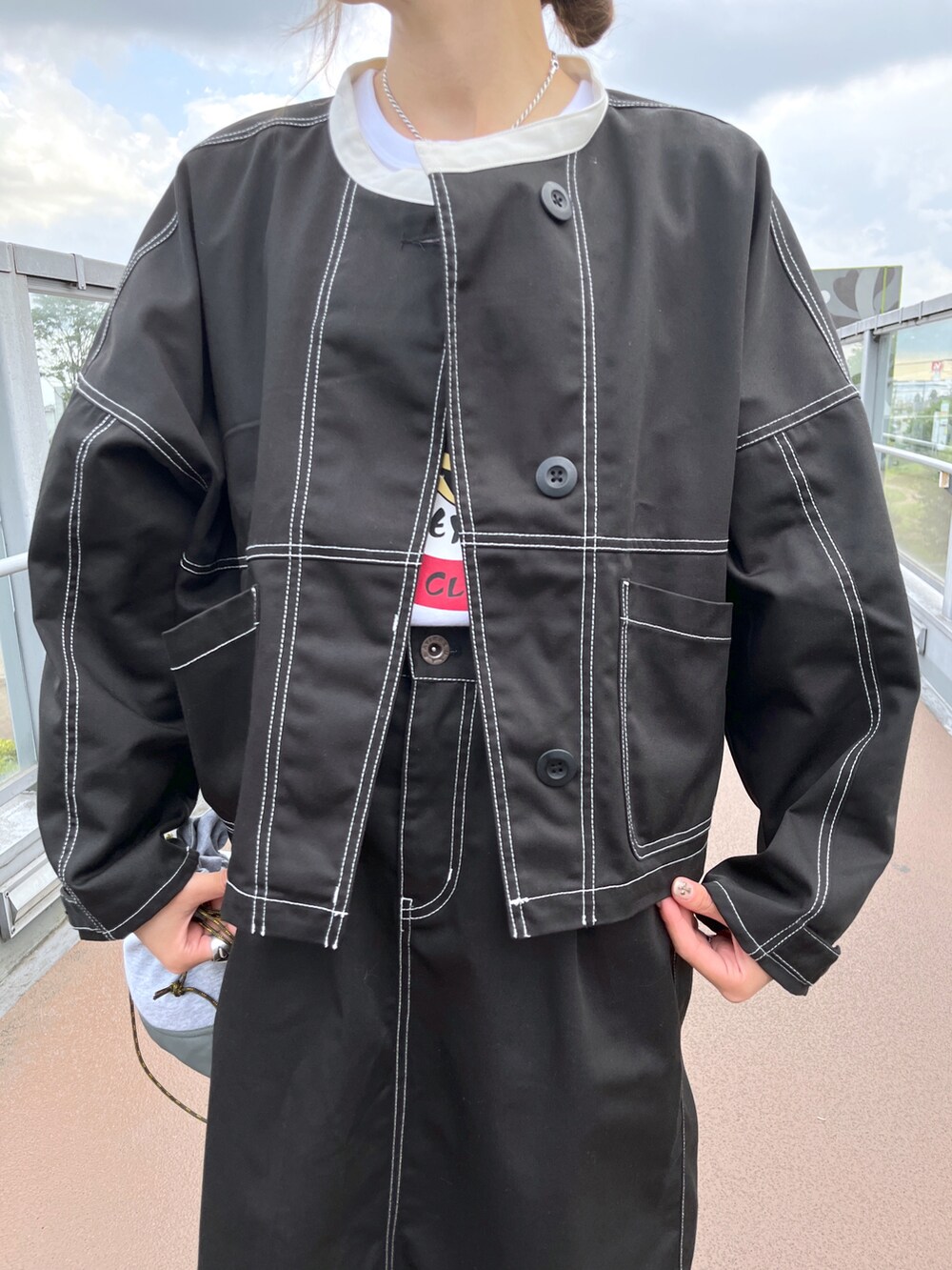 ブラック系のスカート、グレー系のショルダーバッグ、ブラック系のブルゾンを着用したレディースの夏コーディネートの3枚目の写真