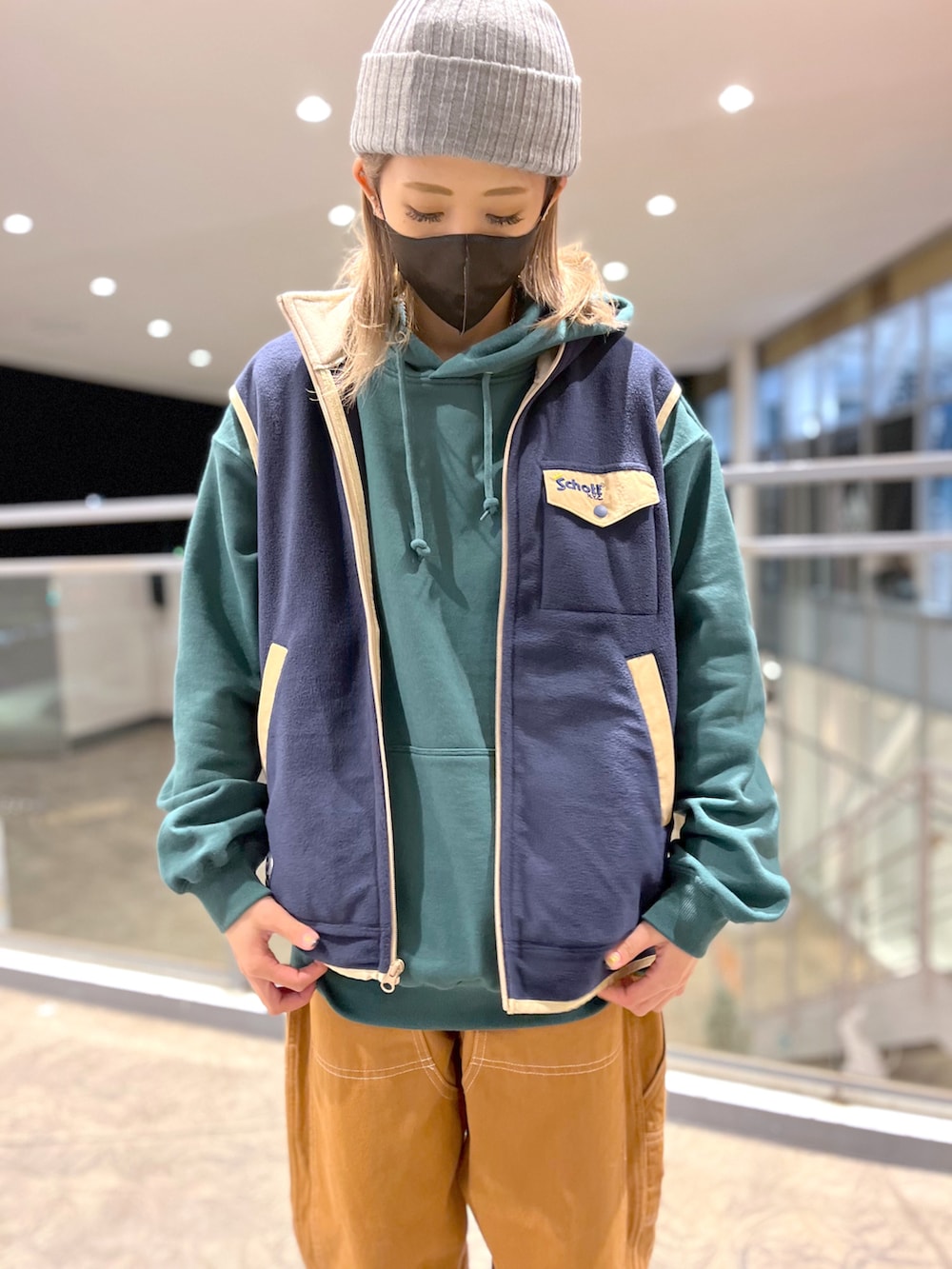 ブラック系のパーカー、ブルー系のベスト、ブラウン系のその他パンツを着用したレディースの冬コーディネートの2枚目の写真