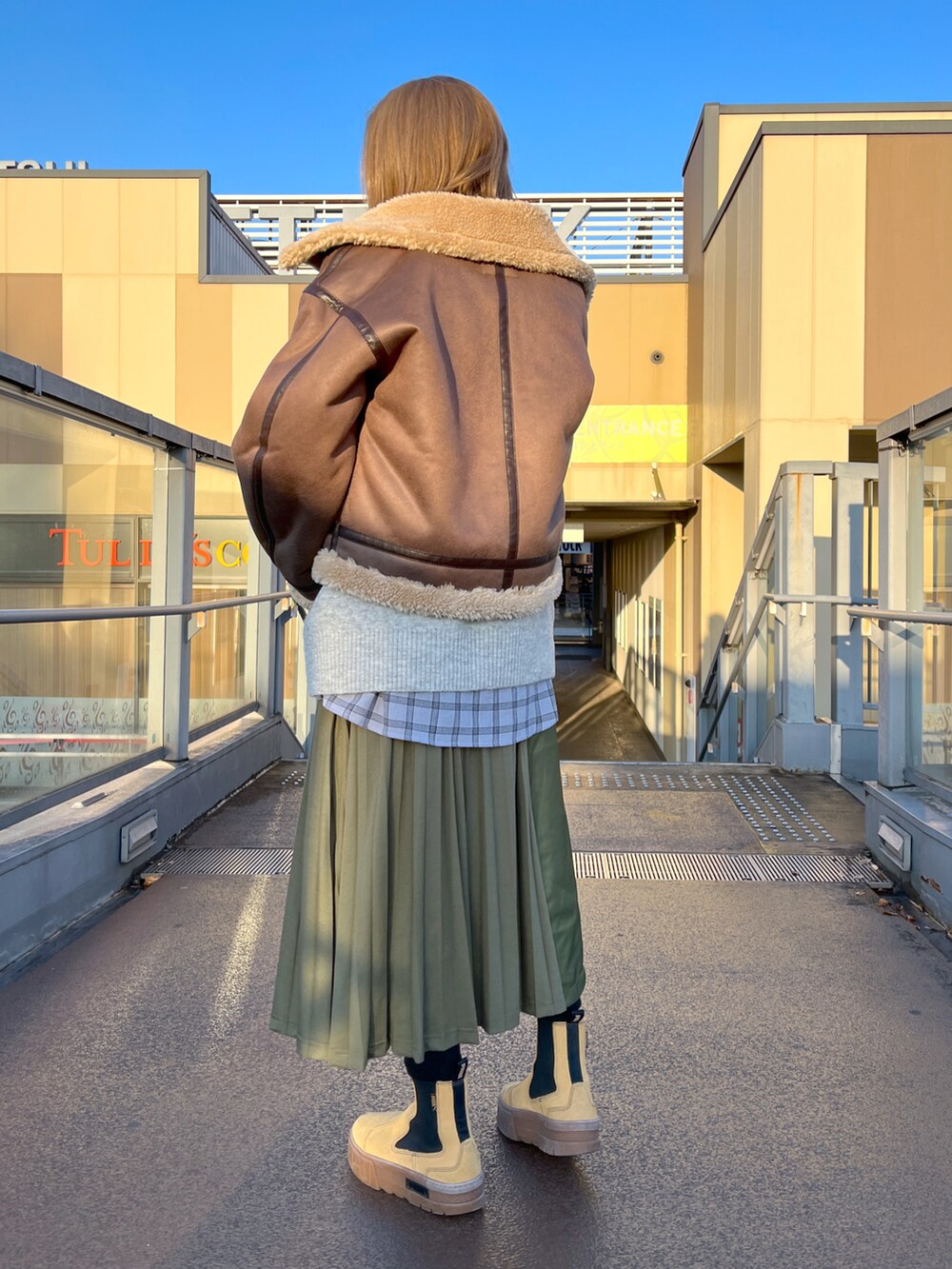 ブラウン系のジャケット/アウター、グレー系のベスト、グリーン系のスカートを着用したレディースの冬コーディネートの2枚目の写真