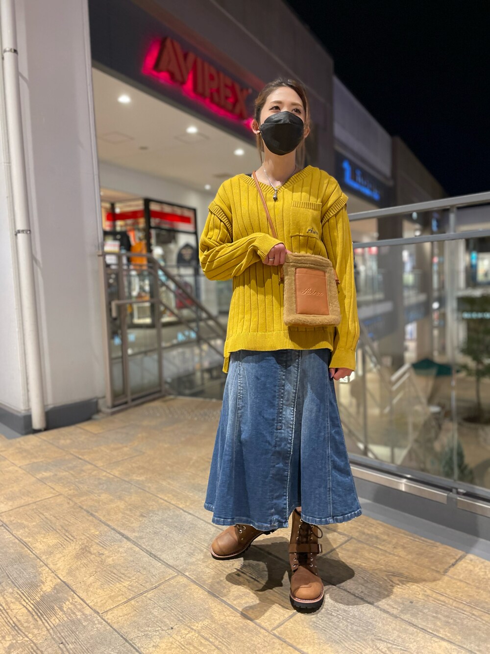 イエロー系のニット/セーター、ブルー系のスカート、ベージュ系のショルダーバッグを着用したレディースの冬コーディネートの2枚目の写真