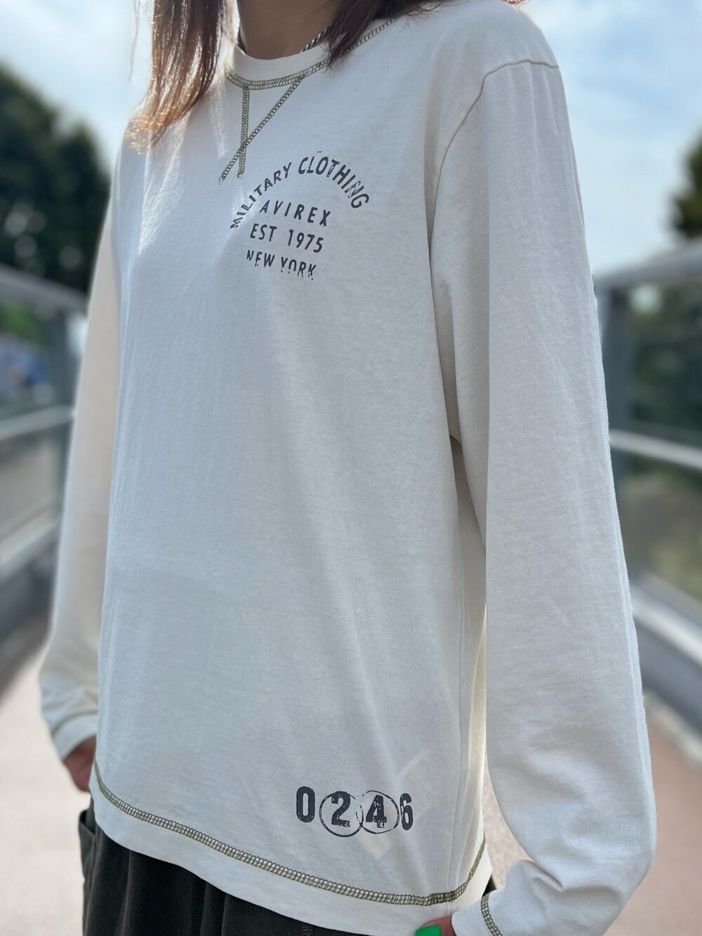 ホワイト系のTシャツ/カットソー、グリーン系のスカート、ブルー系のデニムジャケットを着用したレディースの秋コーディネートの2枚目の写真