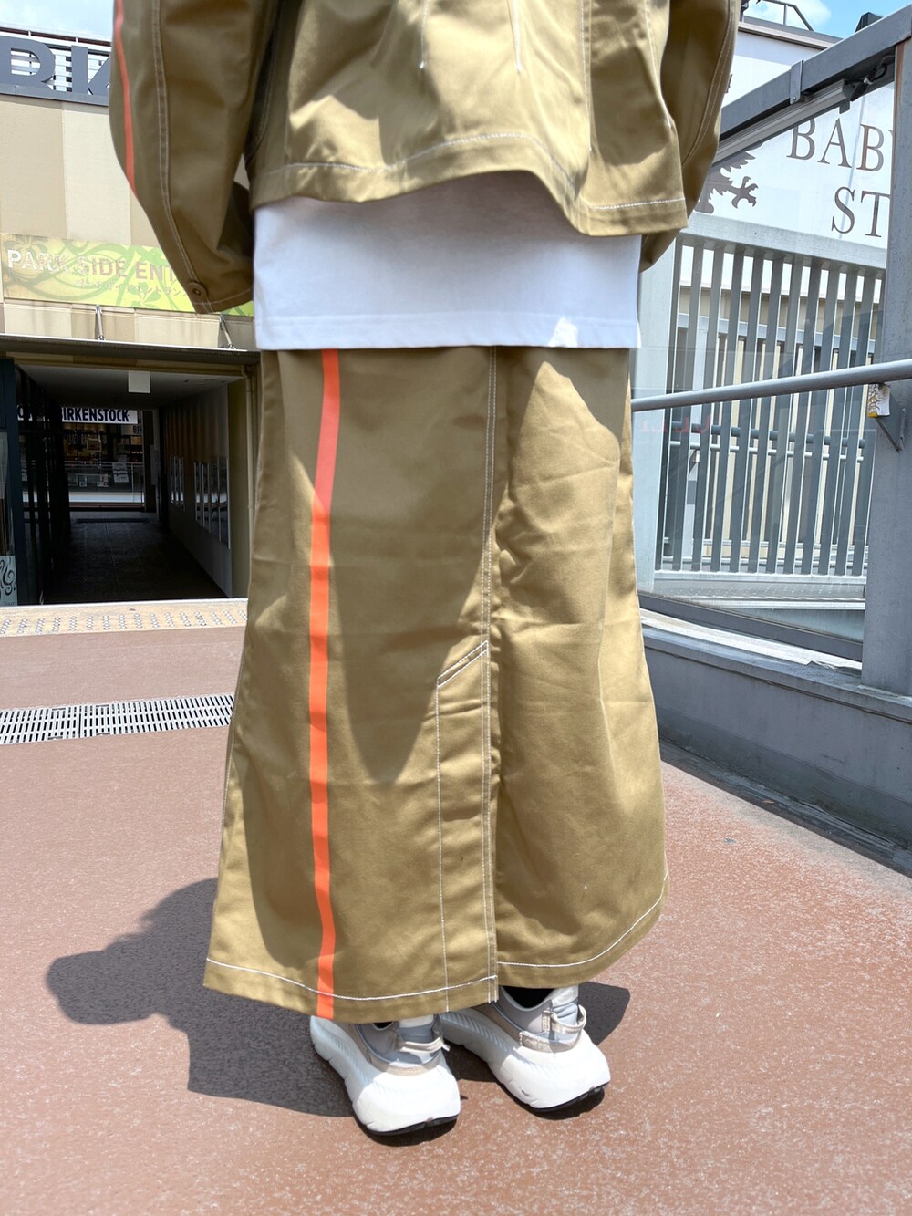 ブラウン系のスカート、ブラウン系のブルゾン、ホワイト系のTシャツ/カットソーを着用したレディースの夏コーディネートの4枚目の写真