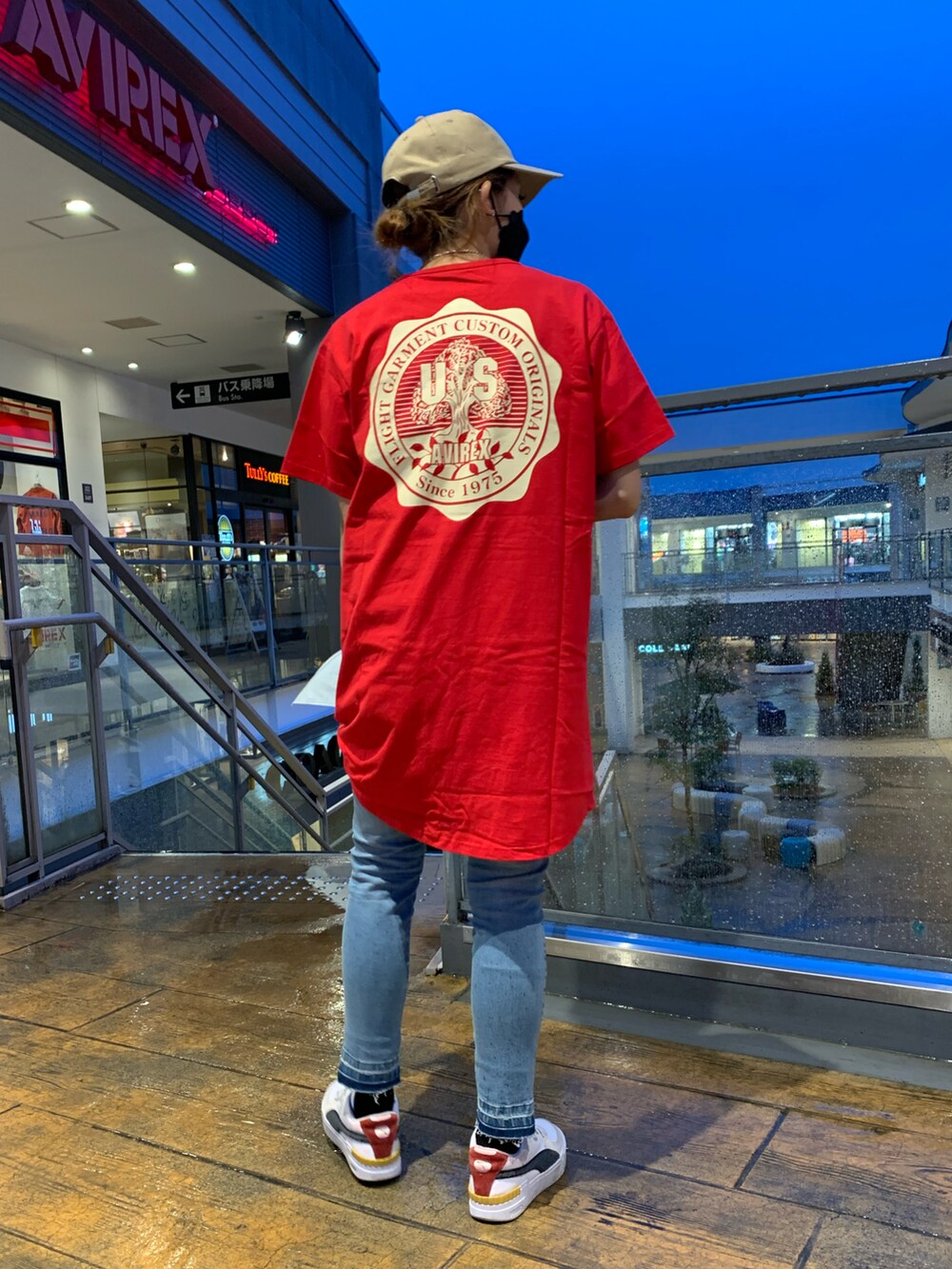 レッド系のワンピース、ブルー系のデニムパンツ、ベージュ系のキャップを着用したレディースの春コーディネートの2枚目の写真