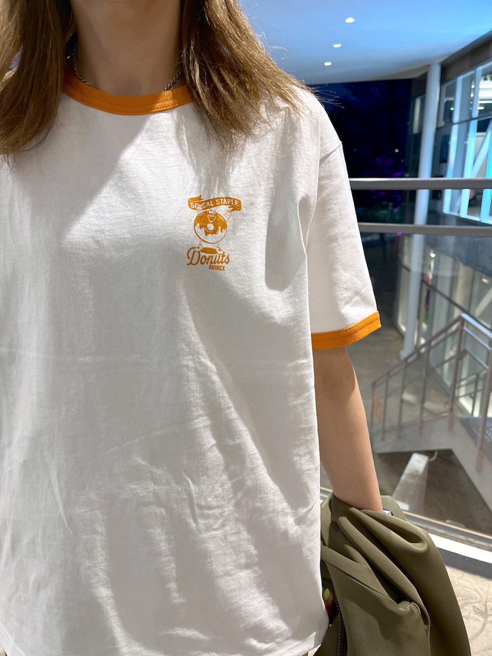 オレンジ系のTシャツ/カットソー、グリーン系のスカート、グリーン系のジャージを着用したレディースの春コーディネートの4枚目の写真