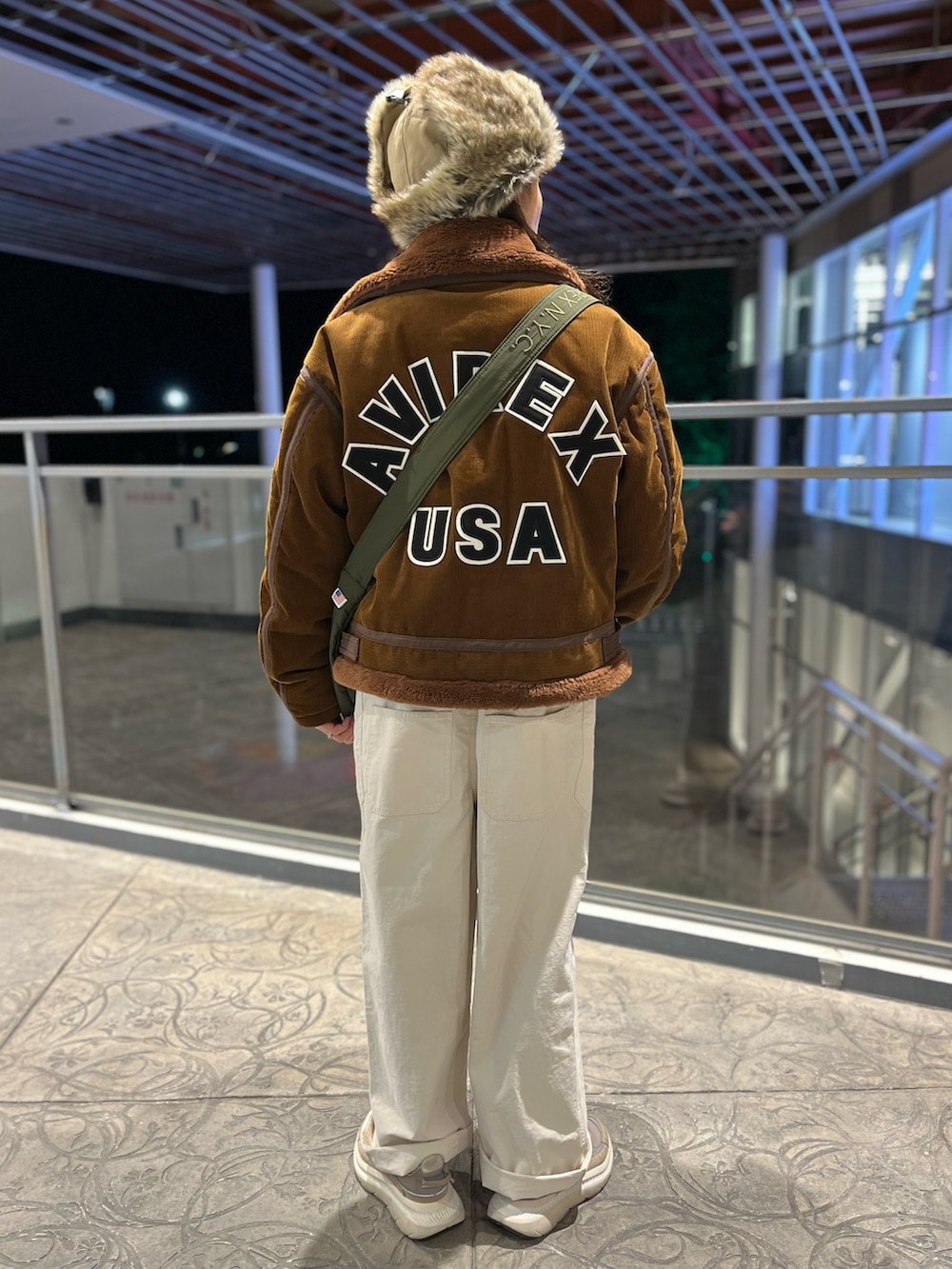 ブラウン系のミリタリージャケット、ベージュ系のスウェット、グリーン系のショルダーバッグを着用したレディースの冬コーディネートの2枚目の写真