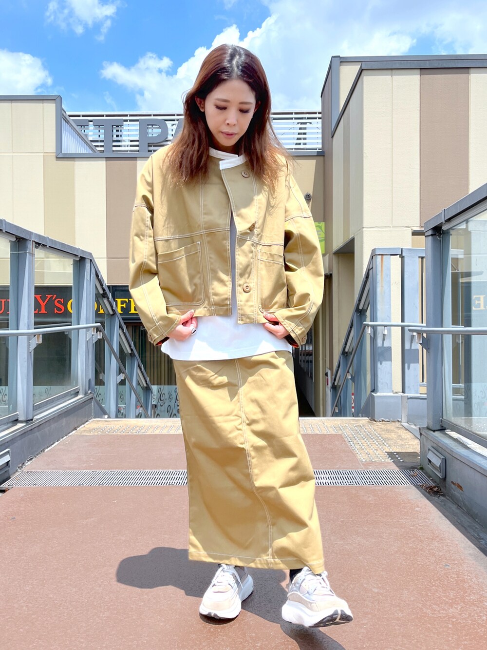 ブラウン系のスカート、ブラウン系のブルゾン、ホワイト系のTシャツ/カットソーを着用したレディースの夏コーディネートの2枚目の写真