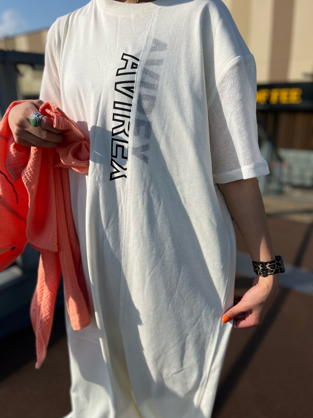 オレンジ系のシャツ/ブラウス、ホワイト系のワンピース、シルバー系のサンダルを着用したレディースの夏コーディネートの3枚目の写真