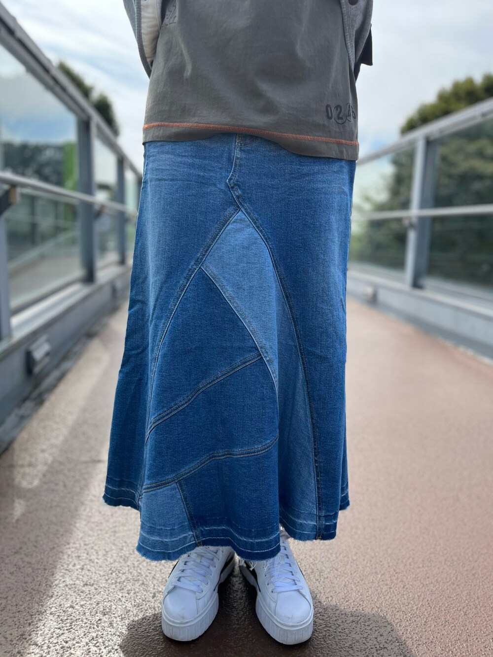 グレー系のカーディガン/ボレロ、グリーン系のTシャツ/カットソー、ブルー系のデニムスカートを着用したレディースの秋コーディネートの3枚目の写真