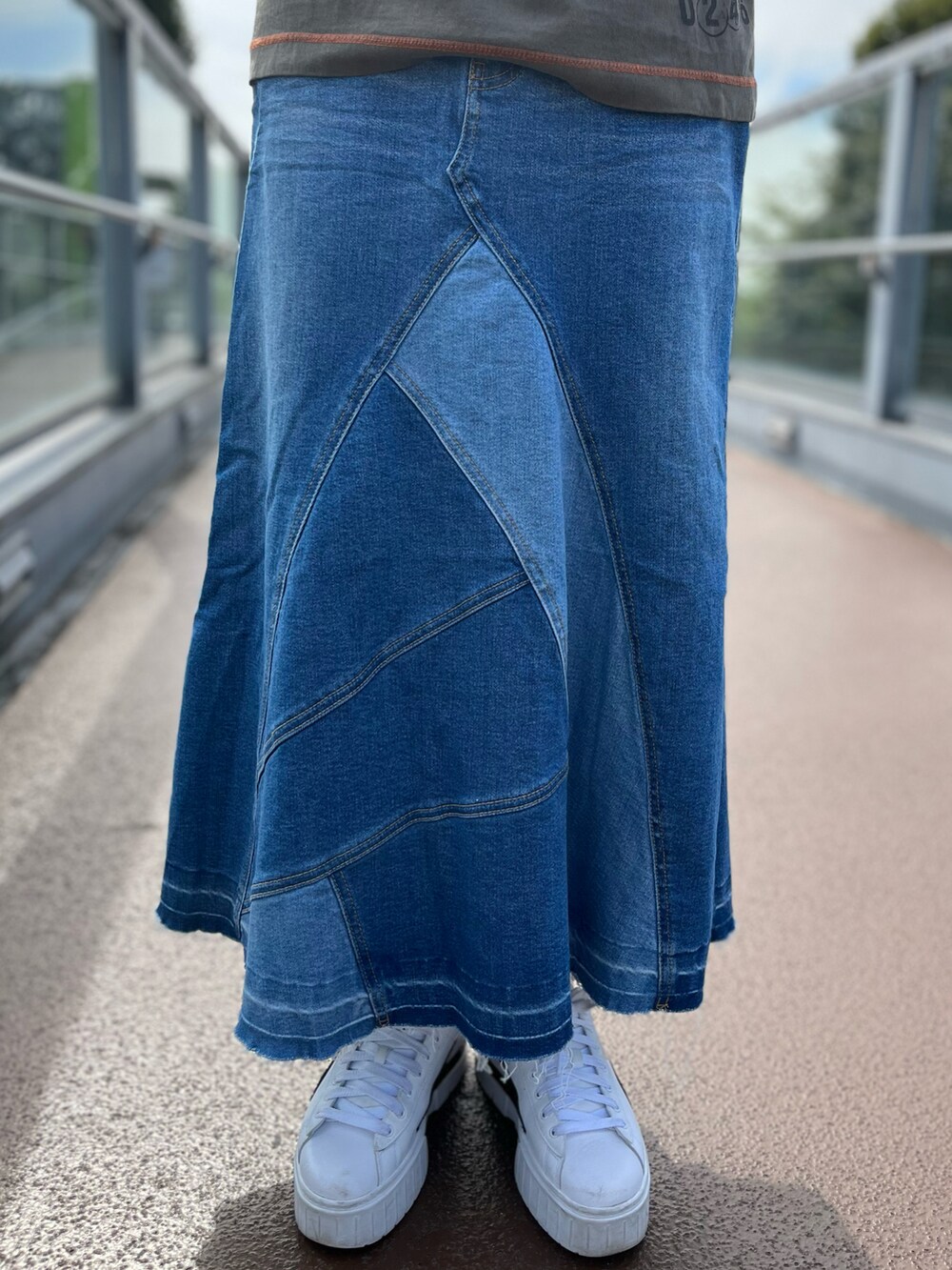 グリーン系のTシャツ/カットソー、グレー系のカーディガン/ボレロ、ブルー系のデニムスカートを着用したレディースの秋コーディネートの3枚目の写真