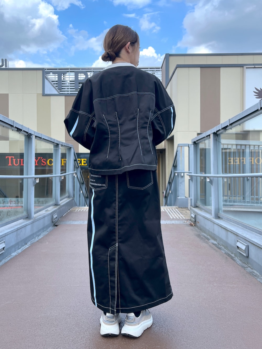 ブラック系のスカート、グレー系のショルダーバッグ、ブラック系のブルゾンを着用したレディースの夏コーディネートの2枚目の写真