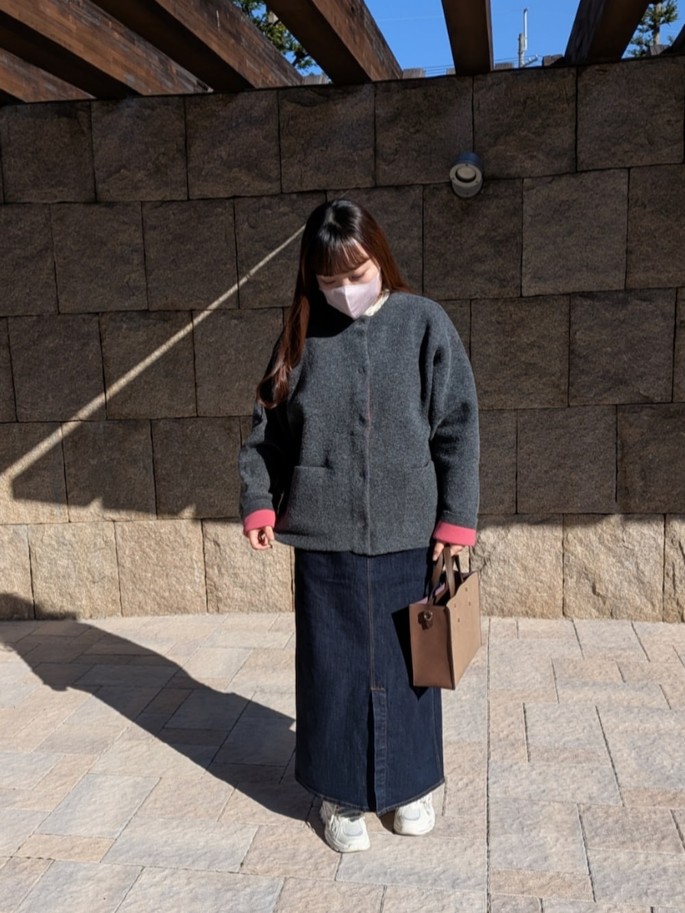 グレー系のカーディガン/ボレロ、ブラウン系のボストンバッグ、ブルー系のデニムスカートを着用したレディースの秋コーディネートの2枚目の写真