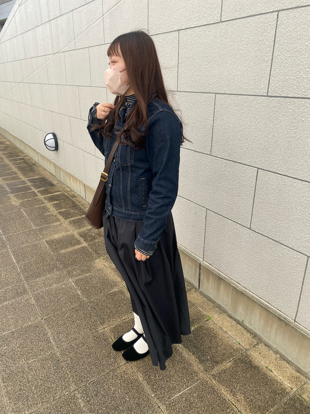 ブルー系のデニムジャケット、ブラック系のTシャツ/カットソー、ブラウン系のショルダーバッグを着用したレディースの秋コーディネートの3枚目の写真