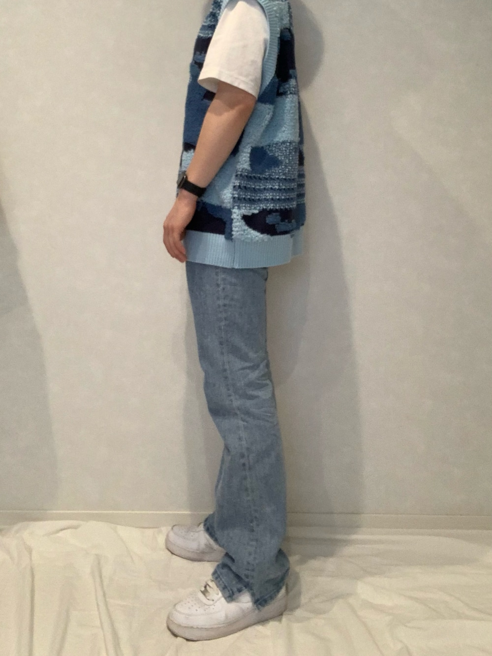 ブルー系のデニムパンツ、ブルー系のベスト、ホワイト系のスニーカーを着用したメンズの春コーディネートの2枚目の写真