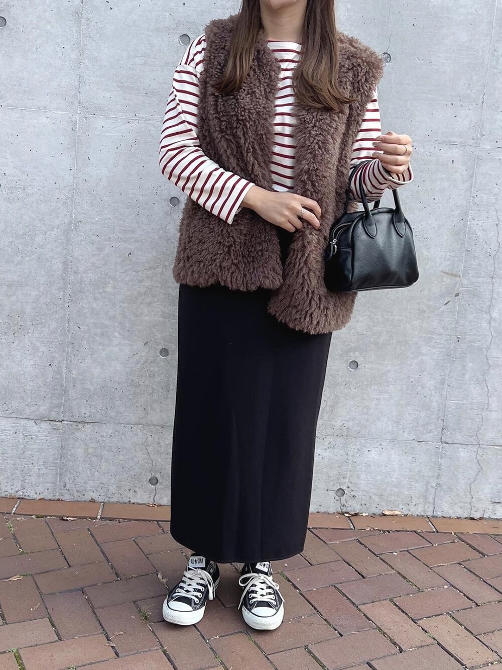 ホワイト系のTシャツ/カットソー、ブラック系のボストンバッグ、ブラウン系のベストを着用したレディースの秋コーディネートの3枚目の写真