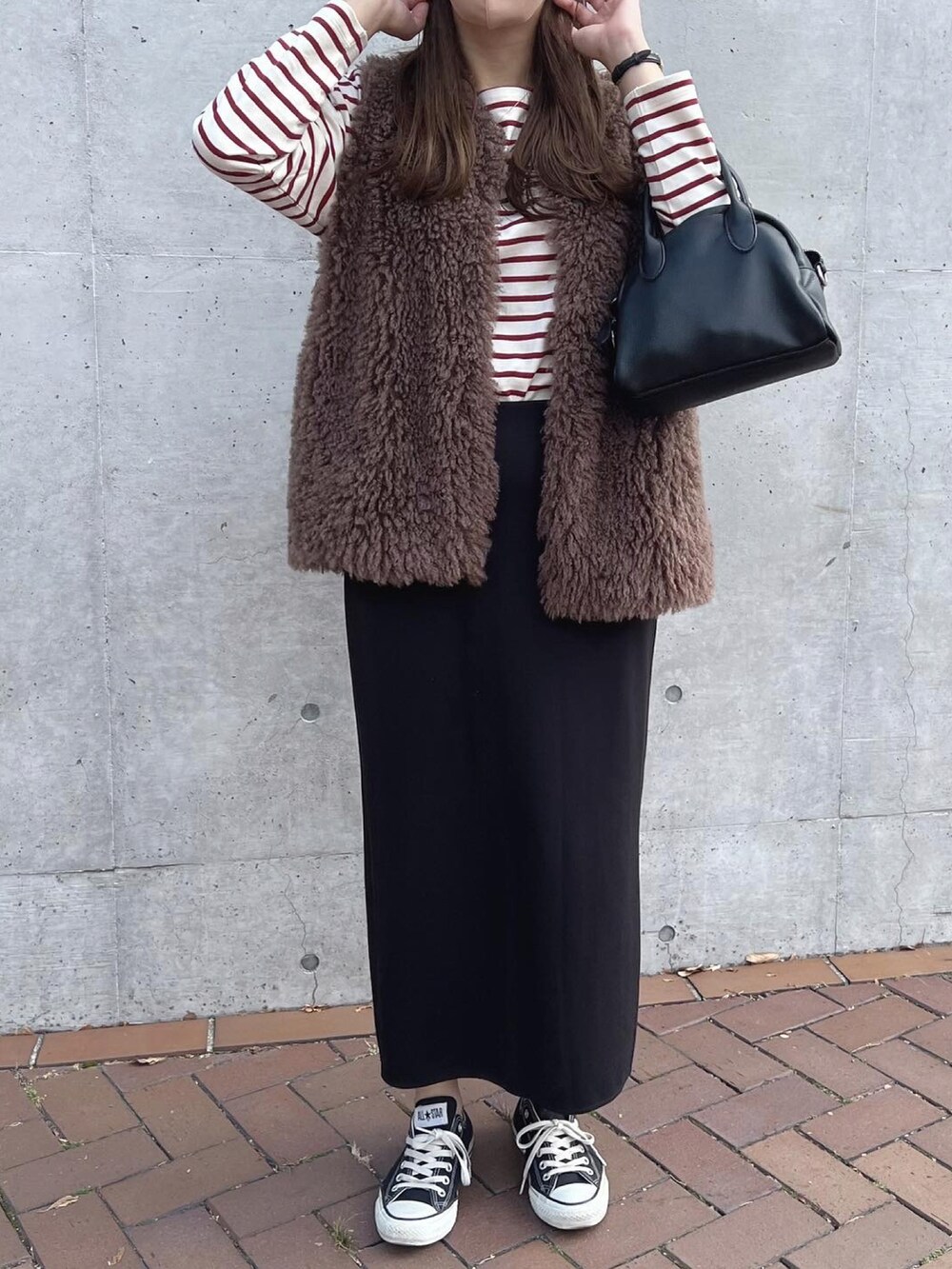 ホワイト系のTシャツ/カットソー、ブラック系のボストンバッグ、ブラウン系のベストを着用したレディースの秋コーディネートの2枚目の写真