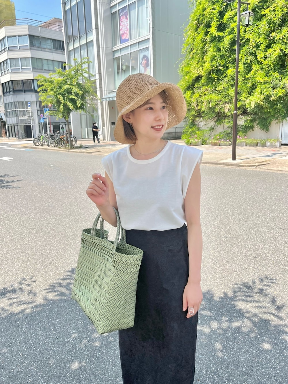 ブラック系のスカート、ホワイト系のTシャツ/カットソー、ベージュ系のハットを着用したレディースの夏コーディネートの3枚目の写真