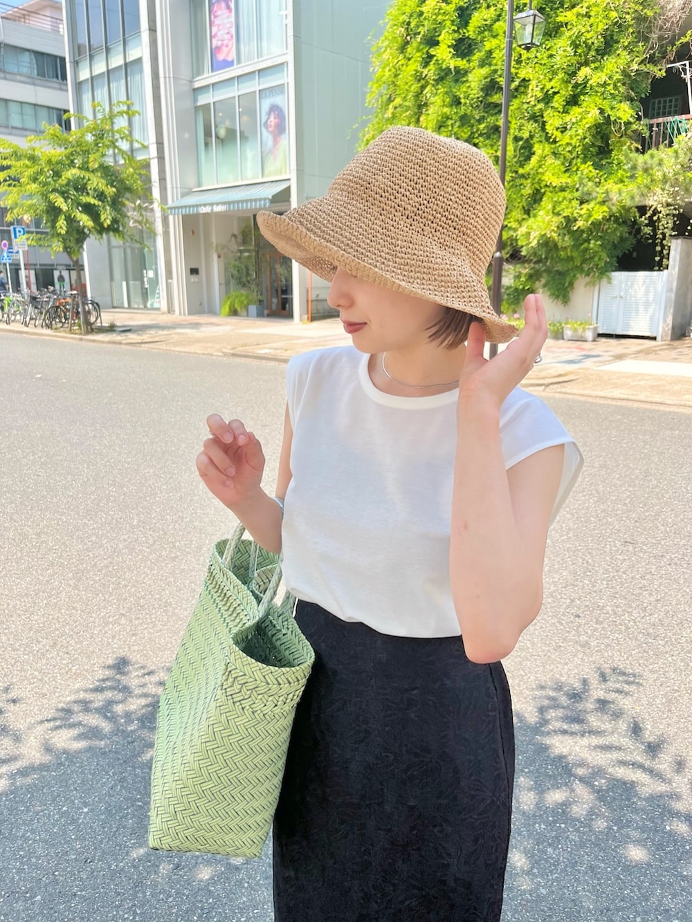 ブラック系のスカート、ホワイト系のTシャツ/カットソー、ベージュ系のハットを着用したレディースの夏コーディネートの4枚目の写真