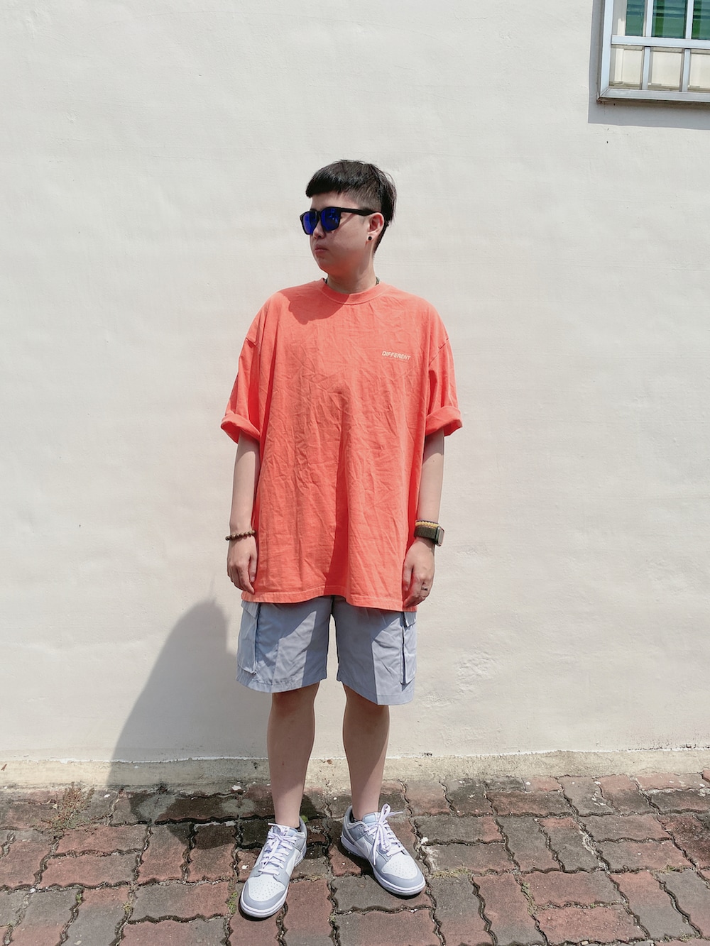 グレー系のスニーカー、シルバー系のカーゴパンツ、オレンジ系のTシャツ/カットソーを着用したメンズの春コーディネートの2枚目の写真