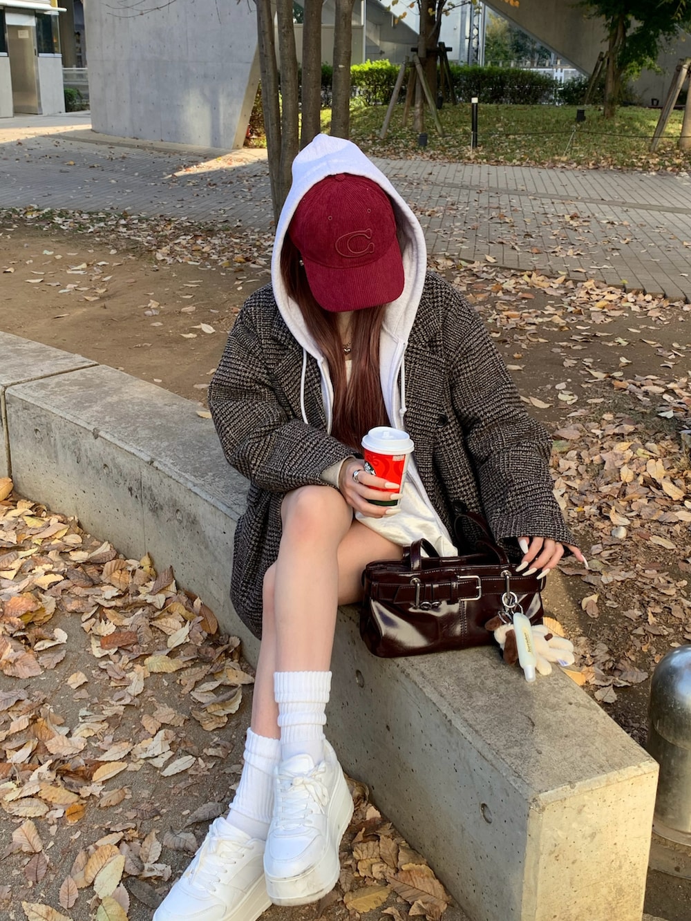 ブラウン系のショルダーバッグ、ブラウン系のテーラードジャケット、レッド系のキャップを着用したレディースの冬コーディネートの2枚目の写真