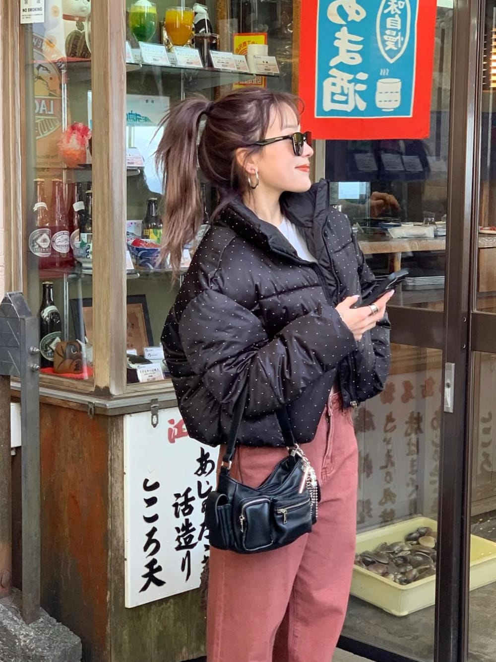 ピンク系のデニムパンツ、ブラック系のハンドバッグ、ホワイト系のスニーカーを着用したレディースの冬コーディネートの2枚目の写真