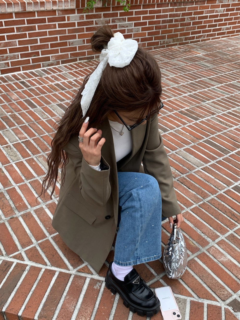 ブルー系のデニムパンツ、ブラウン系のジャケット/アウター、シルバー系のバッグを着用したレディースの秋コーディネートの2枚目の写真