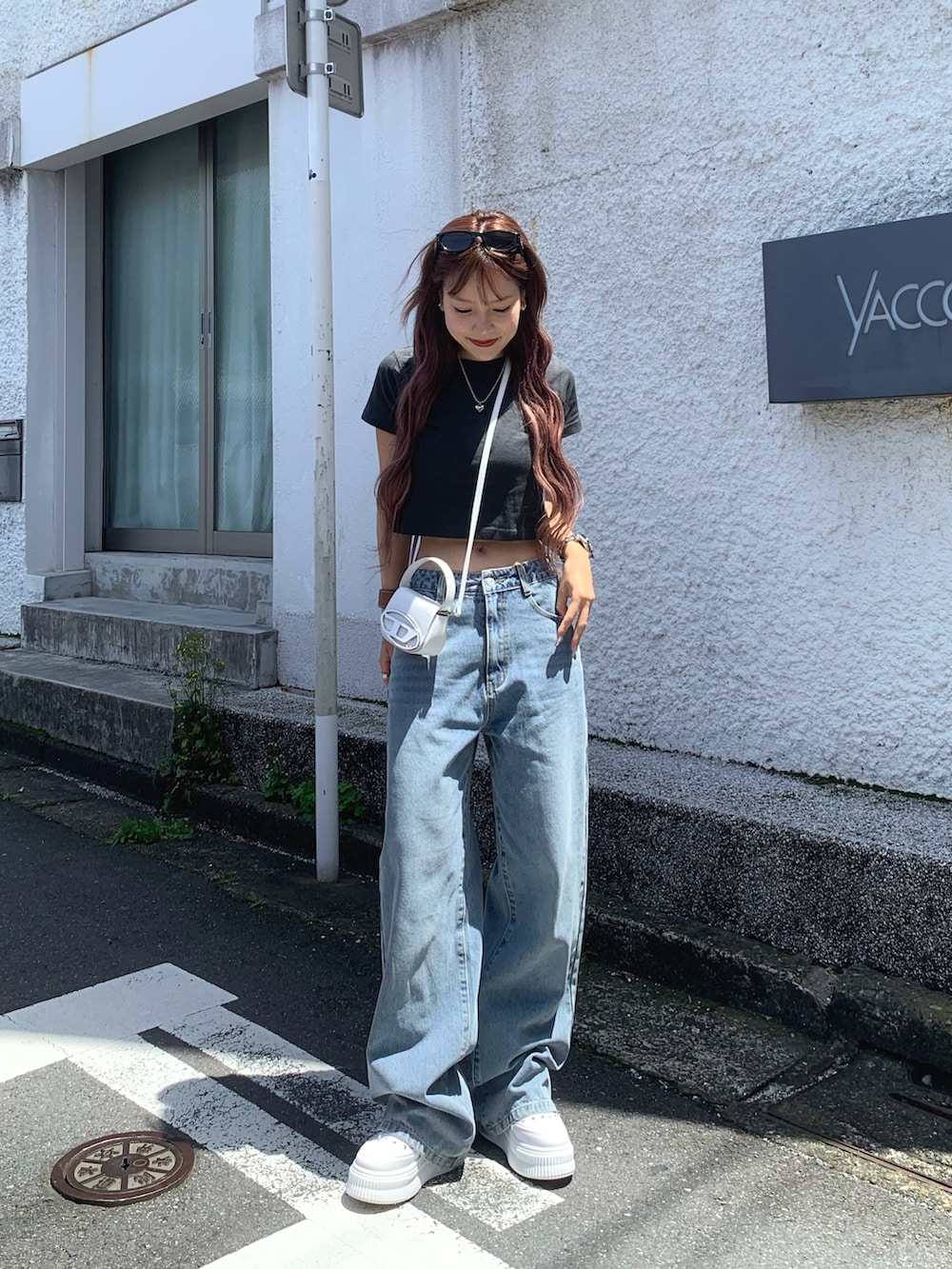 ホワイト系のスニーカー、ブルー系のデニムパンツ、ホワイト系のショルダーバッグを着用したレディースの春コーディネートの2枚目の写真