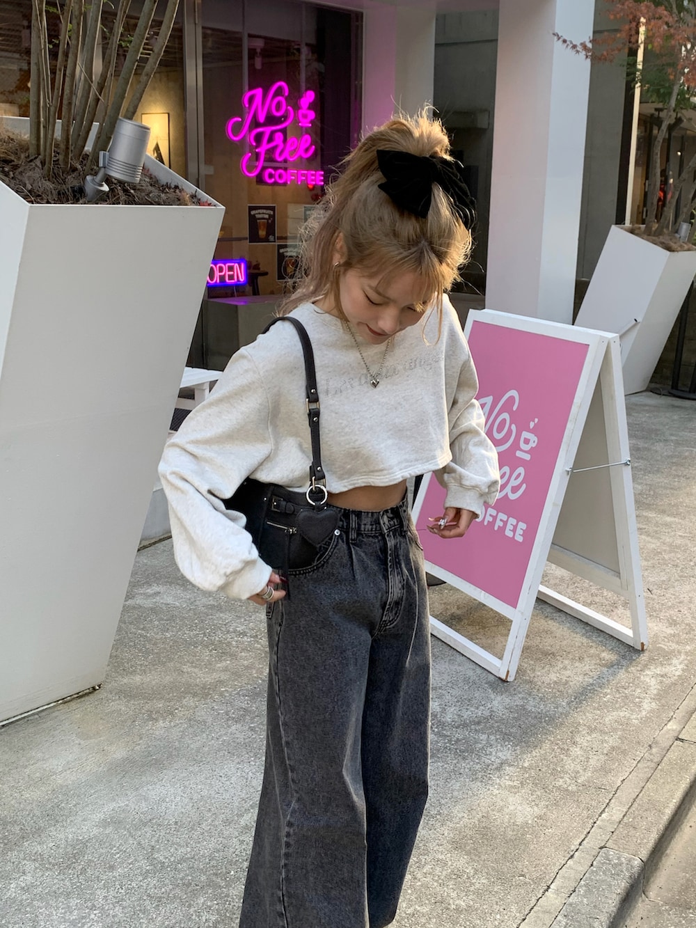 グレー系のショルダーバッグ、ブラック系のデニムパンツ、グレー系のスウェットを着用したレディースの冬コーディネートの2枚目の写真