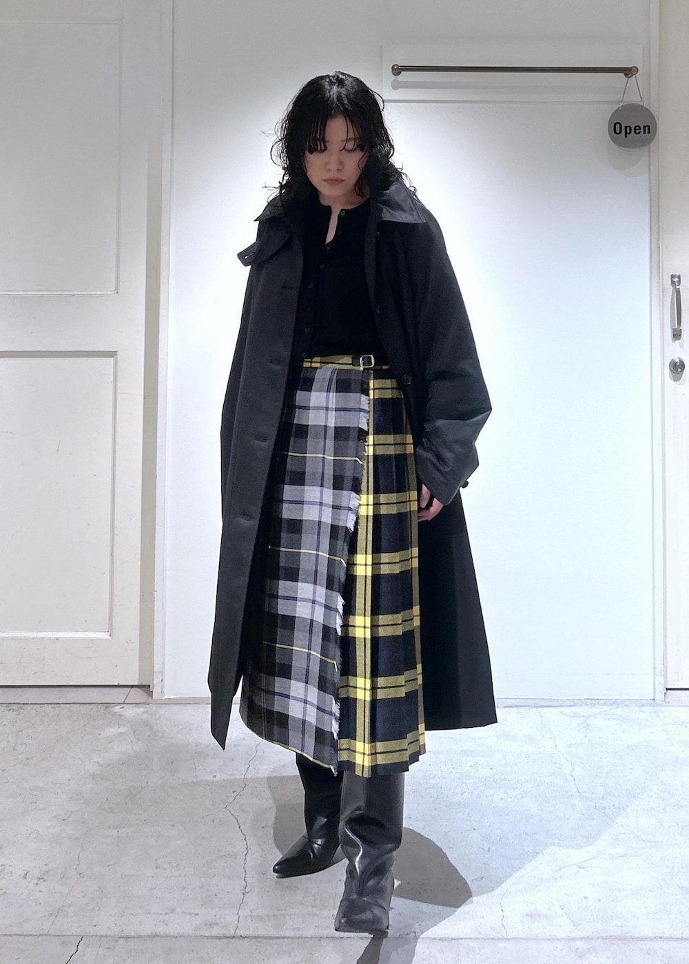 ブラック系のカーディガン/ボレロ、グレー系のスカート、ブラック系のダウンジャケット/コートを着用したレディースの秋コーディネートの2枚目の写真