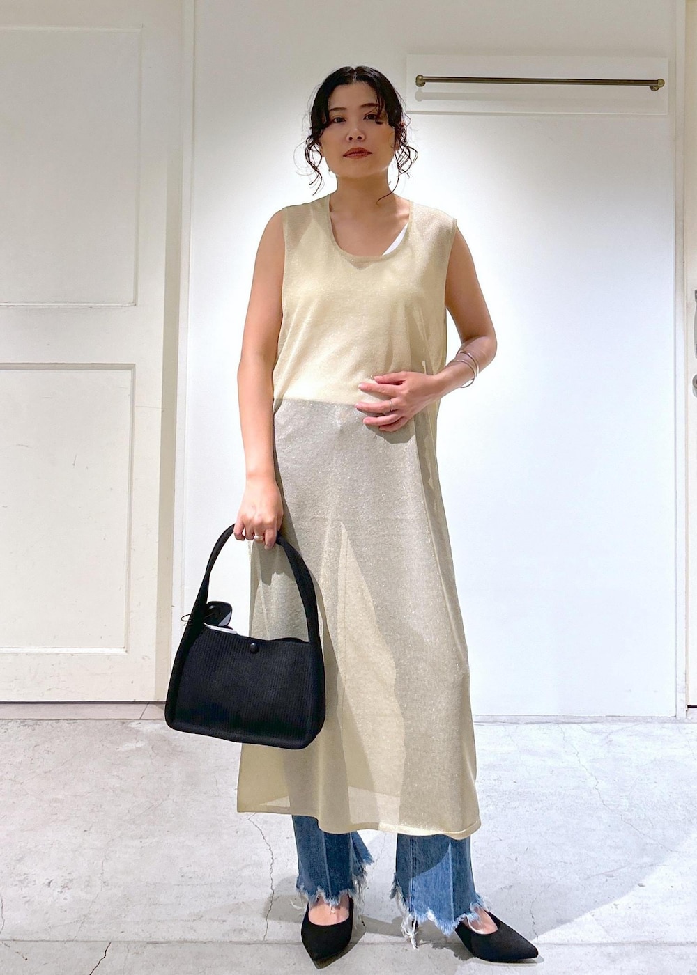 ゴールド系のワンピース、ホワイト系のキャミソール、ブルー系のデニムパンツを着用したレディースの夏コーディネートの3枚目の写真