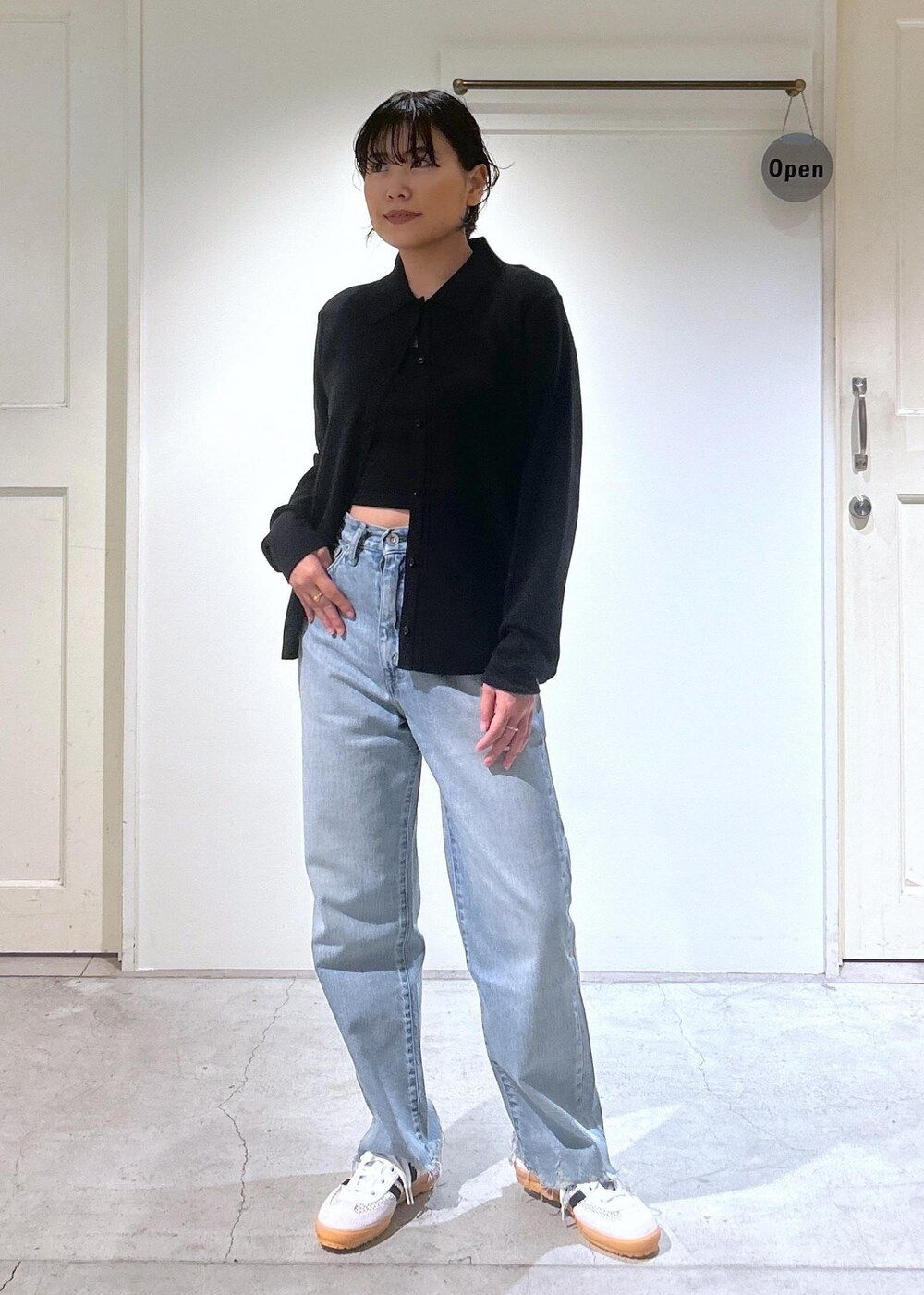 ブラック系のカーディガン/ボレロ、ホワイト系のスニーカー、ブルー系のデニムパンツを着用したレディースの夏コーディネートの6枚目の写真