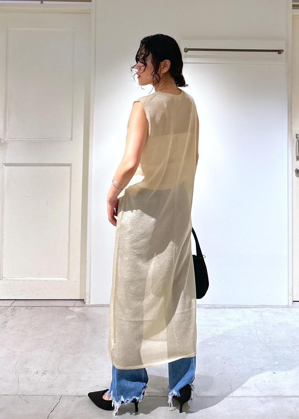 ゴールド系のワンピース、ホワイト系のキャミソール、ブルー系のデニムパンツを着用したレディースの夏コーディネートの5枚目の写真