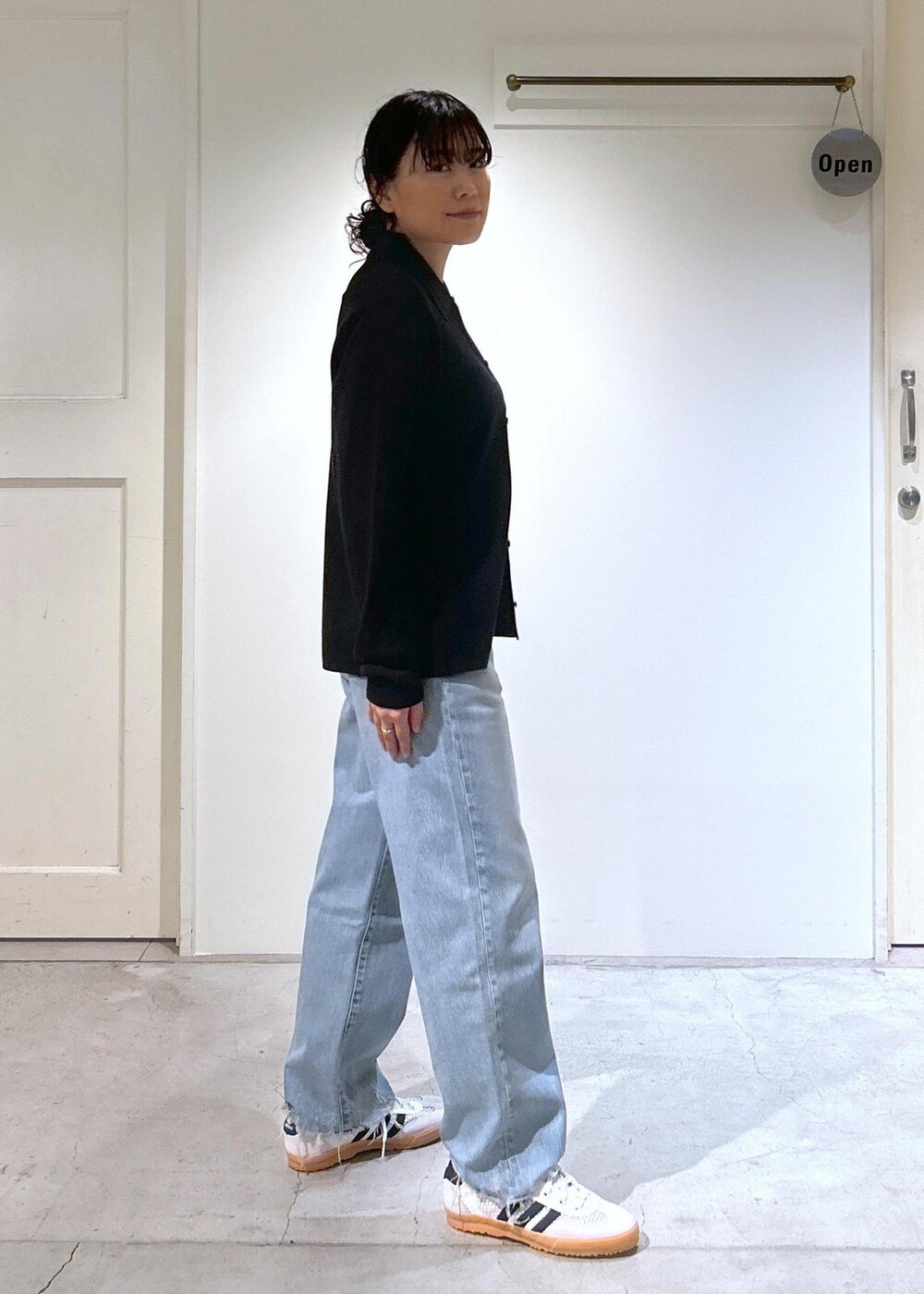 ブラック系のカーディガン/ボレロ、ホワイト系のスニーカー、ブルー系のデニムパンツを着用したレディースの夏コーディネートの3枚目の写真